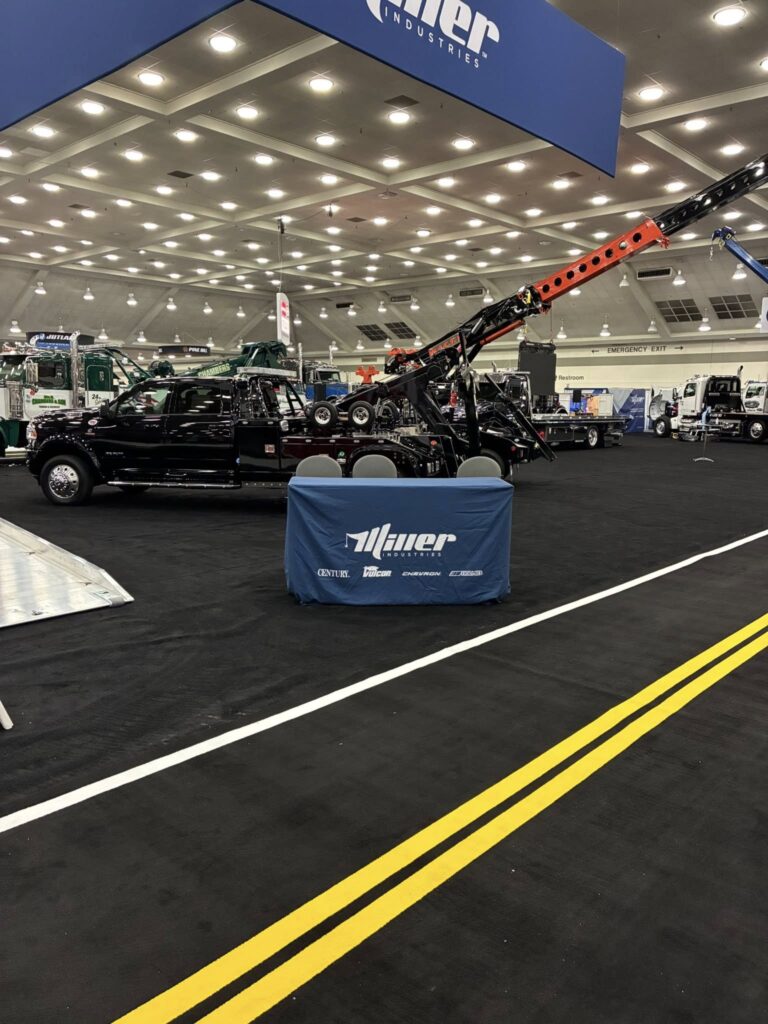 miller booth at the american towman show in Baltimore with our black tow truck in the background.